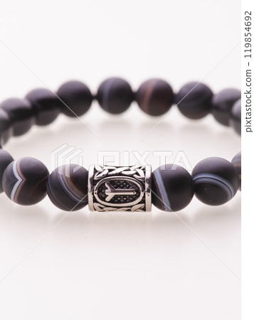 A charming double bracelet in shades of pink, made from natural stone and set against a gray background. The heart charm with cubic zirconia stands out in this close-up top view 119854692