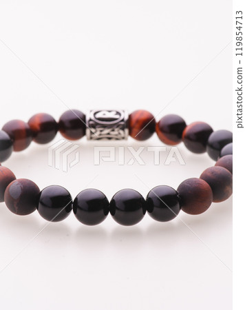 A charming double bracelet in shades of pink, made from natural stone and set against a gray background. The heart charm with cubic zirconia stands out in this close-up top view 119854713