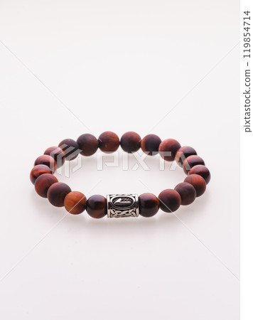 A charming double bracelet in shades of pink, made from natural stone and set against a gray background. The heart charm with cubic zirconia stands out in this close-up top view 119854714