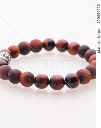 A charming double bracelet in shades of pink, made from natural stone and set against a gray background. The heart charm with cubic zirconia stands out in this close-up top view 119854716