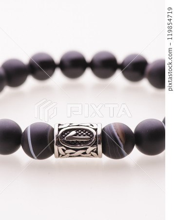 A charming double bracelet in shades of pink, made from natural stone and set against a gray background. The heart charm with cubic zirconia stands out in this close-up top view 119854719