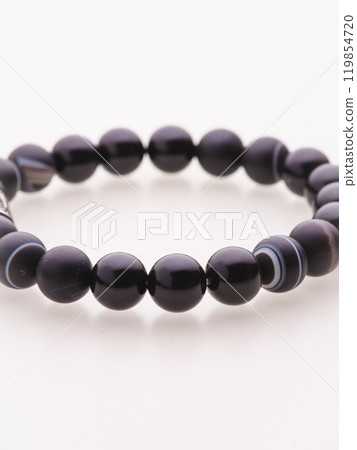 A charming double bracelet in shades of pink, made from natural stone and set against a gray background. The heart charm with cubic zirconia stands out in this close-up top view 119854720