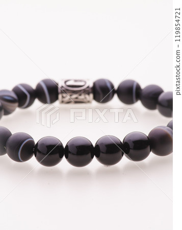 A charming double bracelet in shades of pink, made from natural stone and set against a gray background. The heart charm with cubic zirconia stands out in this close-up top view 119854721