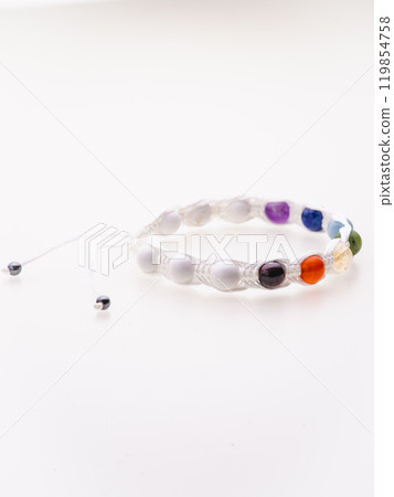 A charming double bracelet in shades of pink, made from natural stone and set against a gray background. The heart charm with cubic zirconia stands out in this close-up top view 119854758