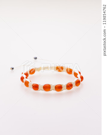 A charming double bracelet in shades of pink, made from natural stone and set against a gray background. The heart charm with cubic zirconia stands out in this close-up top view 119854762