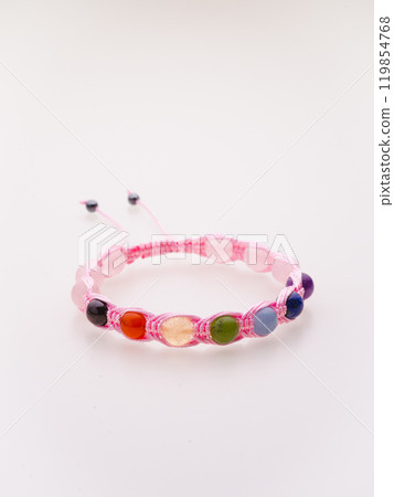 A charming double bracelet in shades of pink, made from natural stone and set against a gray background. The heart charm with cubic zirconia stands out in this close-up top view 119854768