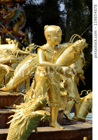 The golden statue of a child holding a fish represents abundance according to ancient Chinese beliefs. 119854878