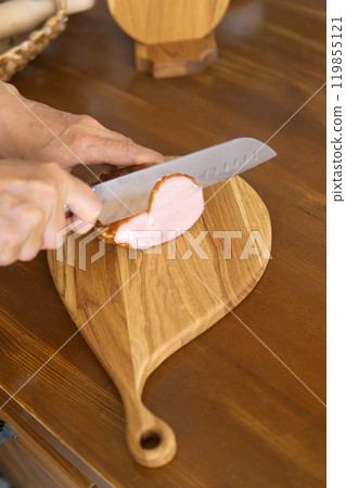 person cutting ham on cutting board person cutting ham on cutting board 119855121