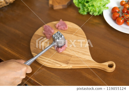 person beats meat with a meat pounder 119855124