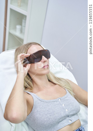 Woman relaxing with protective eye gear during beauty treatment at a modern spa 119855551