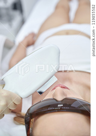 Advanced laser hair removal treatment session with woman wearing protective 119855582