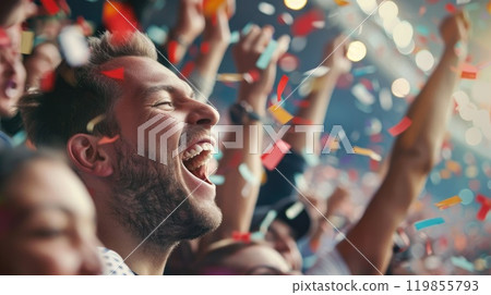 A man is smiling and surrounded by people, with confetti falling around him 119855793