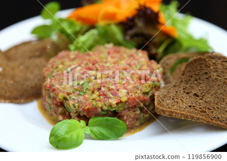 Raw meat tartare for gourmets. Raw meat tartare with spices, croutons and herbs. Beef tartare with capers. Beef tartare with bread slices. 119856900
