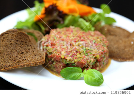 Raw meat tartare for gourmets. Raw meat tartare with spices, croutons and herbs. Beef tartare with capers. Beef tartare with bread slices. Raw meat tartare for gourmets. Raw meat tartare with spices, croutons and herbs. Beef tartare with capers. Beef tartare with bread slices. 119856901