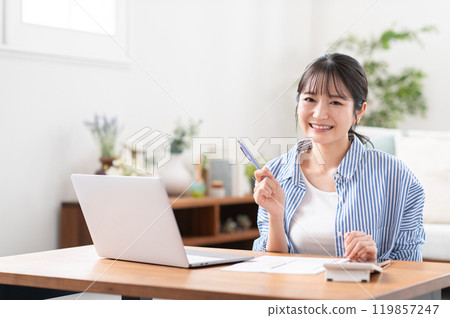 A smiling young woman preparing to file her tax return 119857247