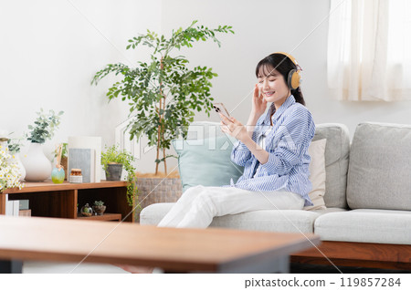 Young woman listening to music in the living room Young woman listening to music in the living room 119857284