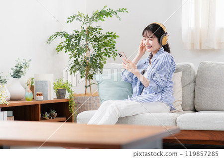 Young woman listening to music in the living room Young woman listening to music in the living room 119857285