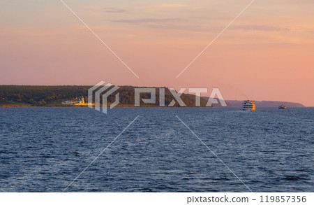 A tourist steamer sails past the Church of the Intercession of the Blessed Virgin Mary on the banks of the Volga River during sunset A tourist steamer sails past the Church of the Intercession of the Blessed Virgin Mary on the banks of the Volga River during sunset 119857356