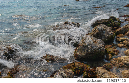 Waves crash on the rocky shore of a tropical island, close-up Waves crash on the rocky shore of a tropical island, close-up 119857410