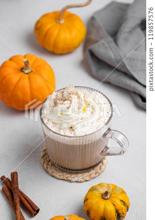Spice latte with whipped cream in glass cup on light background with decorative pumpkins Spice latte with whipped cream in glass cup on light background with decorative pumpkins 119857576