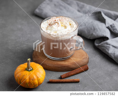 Spice latte with whipped cream in glass cup on wooden board on dark background with pumpkin Spice latte with whipped cream in glass cup on wooden board on dark background with pumpkin 119857582