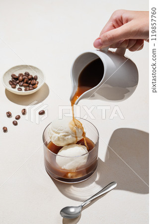 Affogato coffee with vanilla ice cream scoops and espresso poured into a glass on a light background 119857760