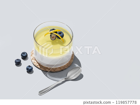 Lemon panna cotta with blueberries in a glass on a blue background with fresh berries, spoons Lemon panna cotta with blueberries in a glass on a blue background with fresh berries, spoons 119857778