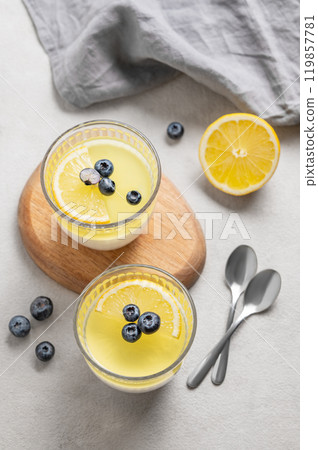 lemon panna cotta with blueberries in two glasses on a light background with berries, napkin 119857781