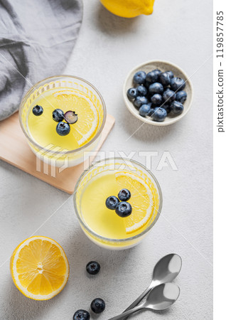 lemon panna cotta with blueberries in two glasses on a light background with berries, napkin  lemon panna cotta with blueberries in two glasses on a light background with berries, napkin  119857785