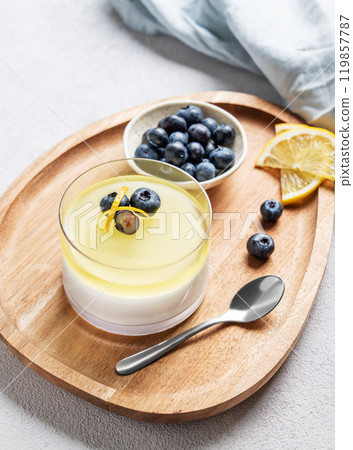 lemon panna cotta with blueberries in glass on a light background with napkin and spoons. lemon panna cotta with blueberries in glass on a light background with napkin and spoons. 119857787
