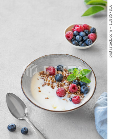 Granola with greek yogurt, raspberries and blueberries in a bowl on a white background 119857816