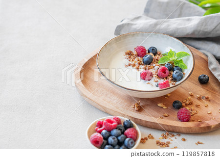 Granola with greek yogurt, raspberries and blueberries in a bowl on a wooden board Granola with greek yogurt, raspberries and blueberries in a bowl on a wooden board 119857818