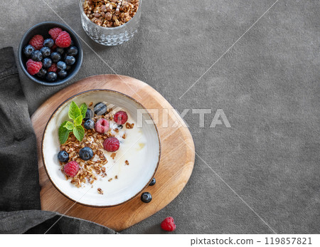 Granola with greek yogurt, raspberries and blueberries in a bowl on a wooden board Granola with greek yogurt, raspberries and blueberries in a bowl on a wooden board 119857821