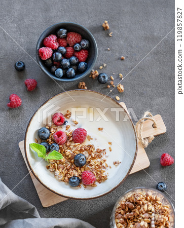 Granola with greek yogurt, raspberries and blueberries in a bowl on a wooden board Granola with greek yogurt, raspberries and blueberries in a bowl on a wooden board 119857827