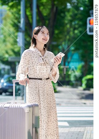 Young woman walking through the city with a suitcase and a smartphone 119857879