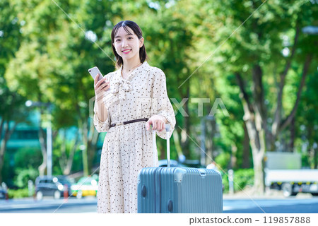 帶著手提箱和智慧型手機在城裡行走的年輕女子 119857888