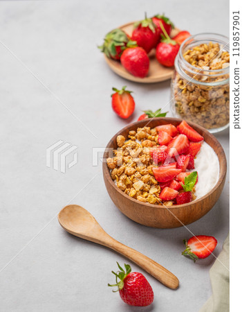 Natural yogurt with granola and strawberries in a wooden bowl on a light background  119857901