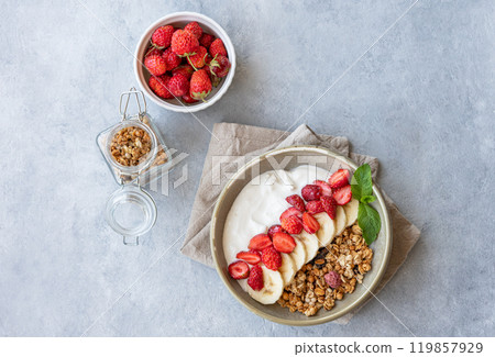 Natural greek yogurt with granola, strawberry and banana in a bowl on a light background Natural greek yogurt with granola, strawberry and banana in a bowl on a light background 119857929
