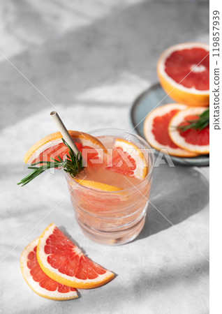 Grapefruit drink with rosemary and ice in a glass on a light background with fresh citrus slices  119857939