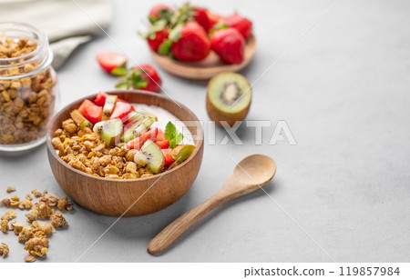 Natural yogurt with granola, kiwi and strawberries in a wooden bowl on a light background Natural yogurt with granola, kiwi and strawberries in a wooden bowl on a light background 119857984