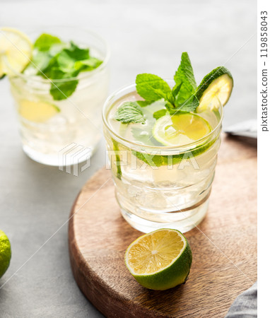 Two glasses lime mojito with mint and ice on a wooden board. Refreshing citrus cocktail  119858043