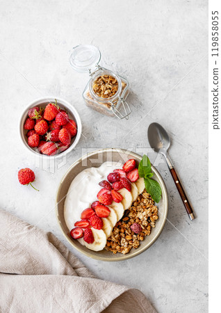 Natural yogurt with granola, strawberry and banana in a bowl on a light background Natural yogurt with granola, strawberry and banana in a bowl on a light background 119858055