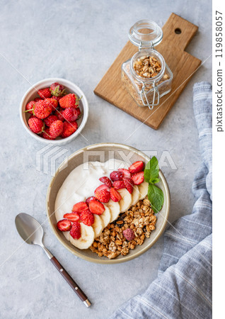 Natural yogurt with granola, strawberry and banana  in a bowl on a light background 119858057