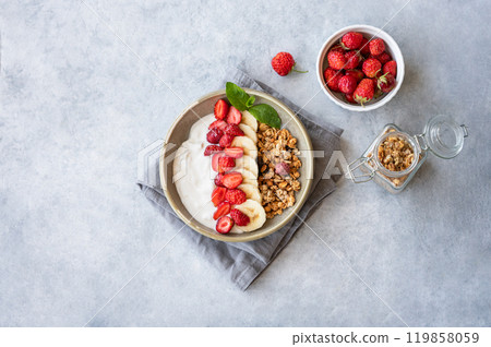 Natural greek yogurt with granola, strawberry and banana in a bowl on a light background Natural greek yogurt with granola, strawberry and banana in a bowl on a light background 119858059