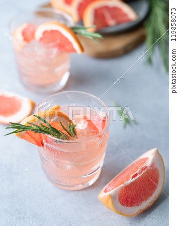 Two glasses grapefruit lemonade drink with rosemary and ice on a blue background Two glasses grapefruit lemonade drink with rosemary and ice on a blue background 119858073