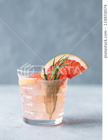 Grapefruit lemonade drink in a glass with rosemary and ice on a blue background. Grapefruit lemonade drink in a glass with rosemary and ice on a blue background. 119858074