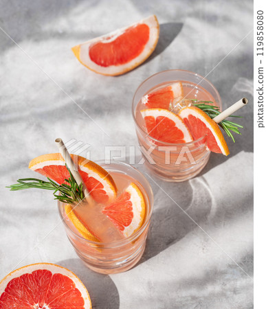 Grapefruit mojito cocktail with rosemary and ice in a two glasses on a light background Grapefruit mojito cocktail with rosemary and ice in a two glasses on a light background 119858080