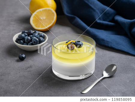 Creamy lemon panna cotta with blueberries in a glass with fresh berries, citrus fruits and napkin Creamy lemon panna cotta with blueberries in a glass with fresh berries, citrus fruits and napkin 119858095