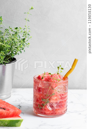 Refreshing watermelon cocktail in glass with thyme and ice on a white marble background  119858130