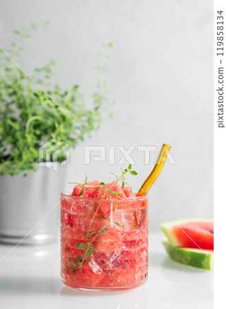 Refreshing watermelon cocktail in glass with thyme and ice on a light background with fresh herbs 119858134